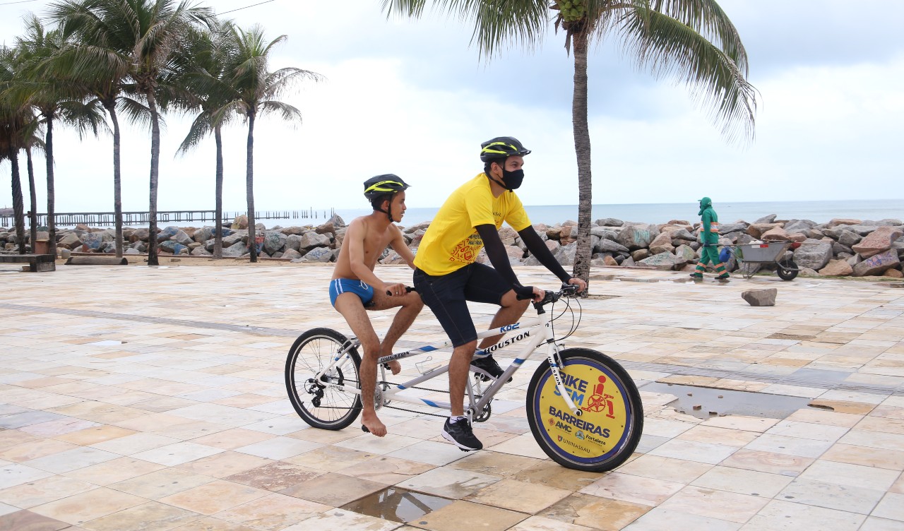 instrutor levando uma pessoa numa bike adaptada